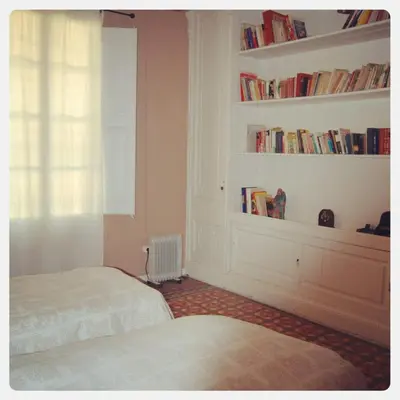 a bedroom with two beds and a window with books at Can plana de baix in San Pol de Mar