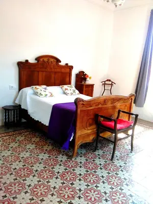 a bedroom with a wooden bed and a chair at Can plana de baix in San Pol de Mar