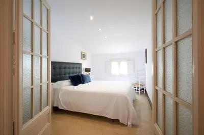 a bedroom with a large white bed with blue pillows at CAL PADRI1871 - 30min to Barcelona, Groups & Families, Beach Stylish House in Premiá de Mar