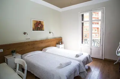 two beds in a white room with a window at Mai & Maud Paralel Apartment in Barcelona