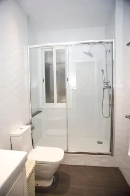 a white bathroom with a shower and a toilet at Mai & Maud Paralel Apartment in Barcelona
