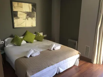 a bedroom with a bed with green and white pillows at Apartamento FIRA Barcelona in Hospitalet de Llobregat