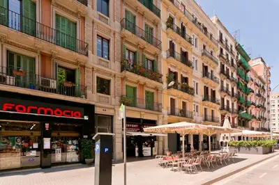 a street with tables and umbrellas in front of a building at Mai & Maud Ronda Apartment in Barcelona