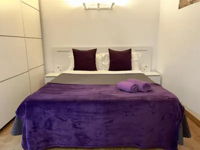 a bedroom with a bed with purple sheets and pillows at Apartahotel Baldiri in Sant Boi del Llobregat