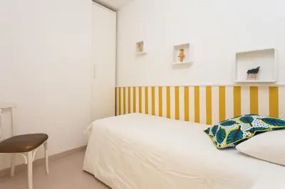 a bedroom with a white bed and a chair at Casa Cosi Letamendi in Barcelona