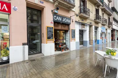 an empty street with tables and chairs in front of a store at Casa Cosi Letamendi in Barcelona