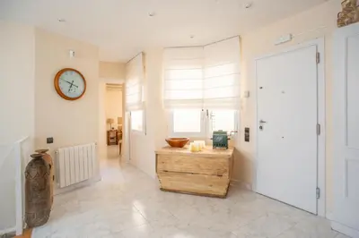 a hallway with a clock on the wall and a wooden table at Casa Cala Balmins in Sitges