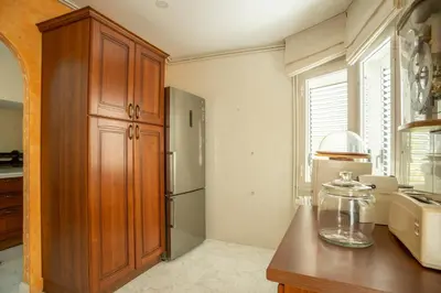 a kitchen with a refrigerator and a wooden cabinet at Casa Cala Balmins in Sitges