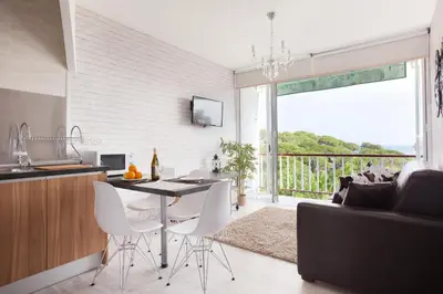 a kitchen and living room with a table and chairs at Apartment Beach Front Sant Pol in San Pol de Mar