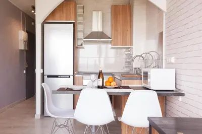 a kitchen with a counter with white chairs in it at Apartment Beach Front Sant Pol in San Pol de Mar