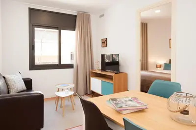 a living room with a table and a room with a bed at Click&Flat Europa Fira Apartments in Hospitalet de Llobregat