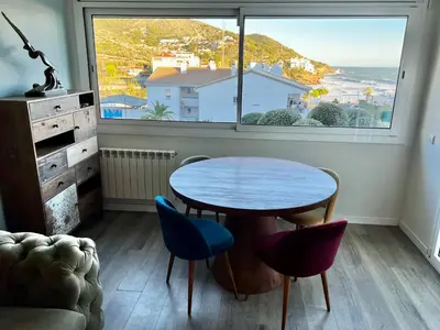 a table and chairs in a room with a large window at La Marina de Aiguadolç in Sitges