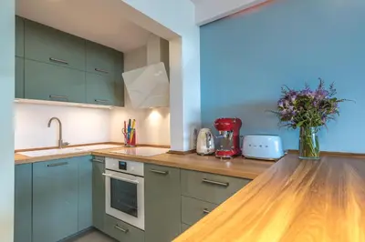 a kitchen with green cabinets and a vase of flowers on a counter at La Marina de Aiguadolç in Sitges