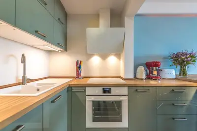 a kitchen with green cabinets and a sink at La Marina de Aiguadolç in Sitges