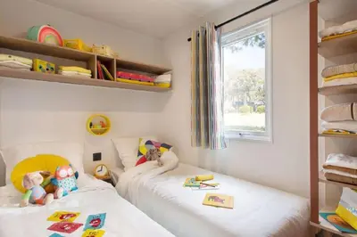 a childs bedroom with two beds and a window at Camping Sènia Caballo de Mar in Pineda de Mar