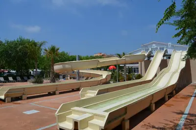 a row of benches with a slide in a park at Camping Sènia Caballo de Mar in Pineda de Mar