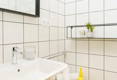 a bathroom with white tile walls and a sink at BYPILLOW Wander in Barcelona