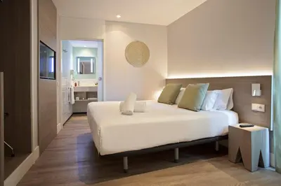 a bedroom with a large white bed and a bathroom at Niu Barcelona Hotel in Barcelona
