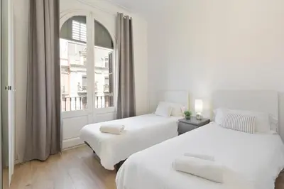 two beds in a white room with a window at Suites4days Gaudi Eixample in Barcelona