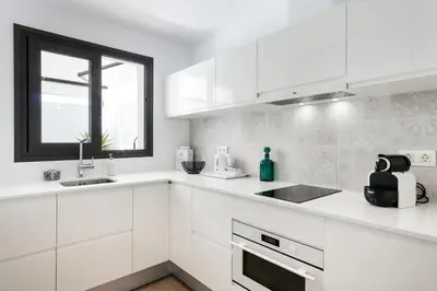 a white kitchen with white cabinets and a window at Destino Sitges in Sitges