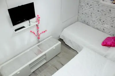a white room with a bed and a tv on a wall at Cosmo Grey in Hospitalet de Llobregat