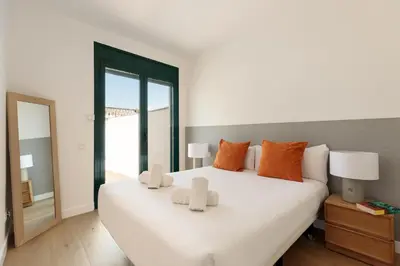 a bedroom with a large white bed with orange pillows at Ola Living Merce in Barcelona