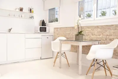 a white kitchen with a table and white chairs at Studio Relax by Hello Homes Sitges in Sitges