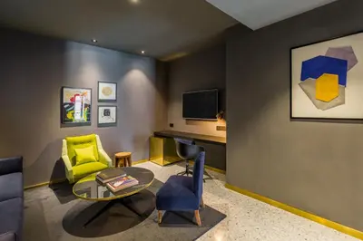 a living room with a table and a yellow chair at Room Mate Collection Gerard, Barcelona in Barcelona