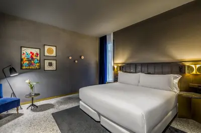 a bedroom with a large white bed and a blue chair at Room Mate Collection Gerard, Barcelona in Barcelona
