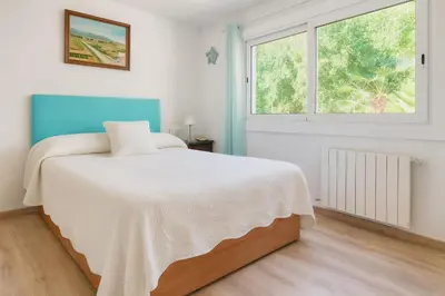 a white bedroom with a bed and a window at Next to the sea 20' from Barcelona in Premiá de Mar