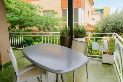 a white table and chairs on a balcony with plants at Next to the sea 20' from Barcelona in Premiá de Mar