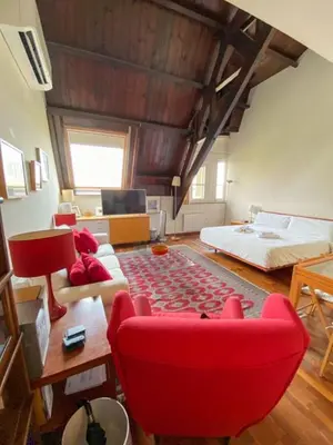 a living room with a red chair and a bed at Passeig de Gracia Studio Loft in Barcelona