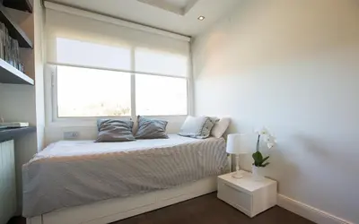 a small bedroom with a bed with a window at Gava Beach 1st Line in Gavà