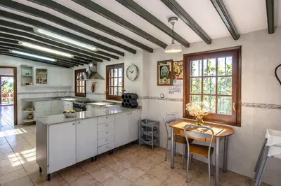 a kitchen with white cabinets and a table with chairs at Catalunya Casas Nature and Tranquility for 24 pax - 30km to beach in Sant Pere de Vilamajor