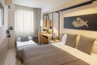 a hotel room with two beds and a desk at Hotel Denit Barcelona in Barcelona