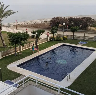 a swimming pool with two children playing in it next to the beach at Apartment Foix in Cubelles