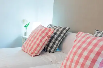 a white bed with four pillows on it at Apartamentos Cornellalux 2 in Cornellà de Llobregat