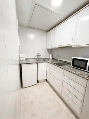 a kitchen with white cabinets and a sink and a microwave at Aparthotel Solifemar in Castelldefels
