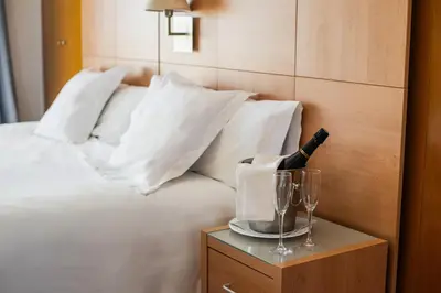 a bed with a bottle of wine and glasses on a table at Aparthotel Solifemar in Castelldefels