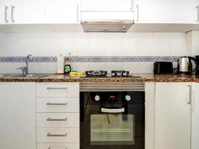 a kitchen with white cabinets and a black oven at Parellades Apartment by Hello Homes Sitges in Sitges