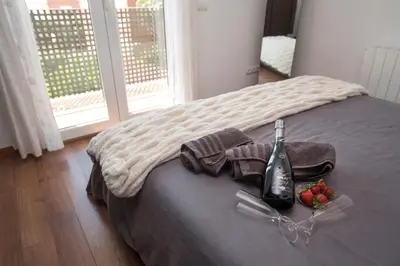 a bed with a bottle of wine and fruit on it at Vilamarlux I in Vilassar de Mar