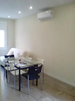 a living room with a glass table and a bed at Castel Apartments in Hospitalet de Llobregat