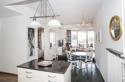 a kitchen and dining room with white cabinets and a table at The Gran Via Penthouse in Barcelona