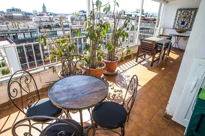 a table and chairs on a balcony with a view at The Gran Via Penthouse in Barcelona