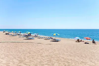a group of people sitting on a beach with umbrellas at Vivalidays Yolanda in Calella