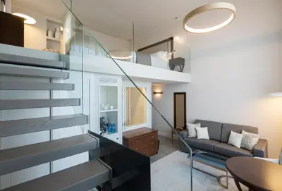 a living room with a staircase leading up to a loft at Hotel Casa Vilella 4* Sup in Sitges