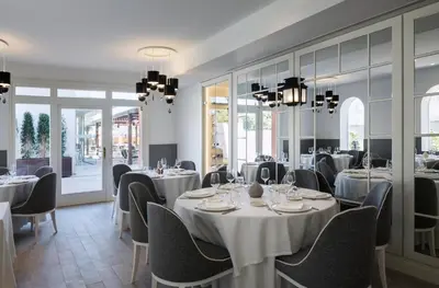 a restaurant with white tables and chairs and windows at Hotel Casa Vilella 4* Sup in Sitges