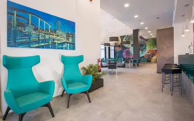 a waiting room with blue chairs and a painting on the wall at Hotel Venture Sant Cugat in Sant Cugat del Vallès