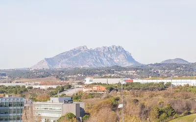 a mountain in the distance with a city and buildings at Hotel Venture Sant Cugat in Sant Cugat del Vallès