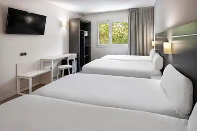 a hotel room with two beds and a desk at B&B HOTEL Barcelona Rubí in Rubí